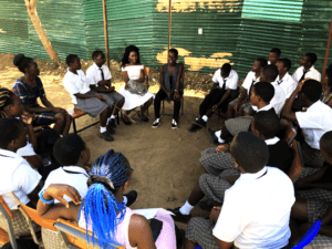 Group of girls sitting on chairs in a circle, having a discussion.