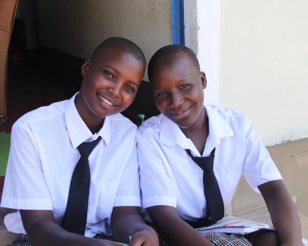 Two WISER girls are sitting next to one another and smiling for a photo.
