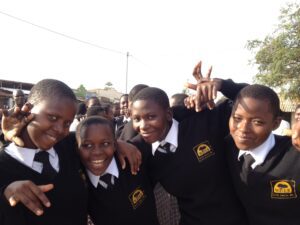 Group of WISER girls hugging and holding up their hands.